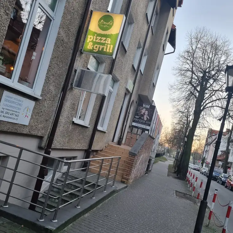 Kamienica z zielonym szyldem restauracji przy ulicy