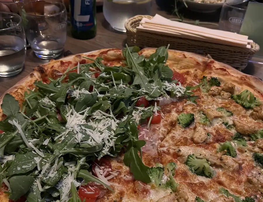 Pizza z rukolą i parmezanem na stole