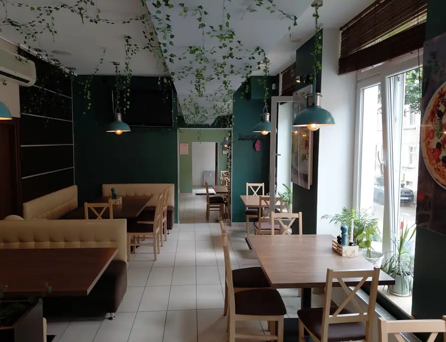 Sala z zielonymi ścianami, kanapami i bluszczem pod sufitem